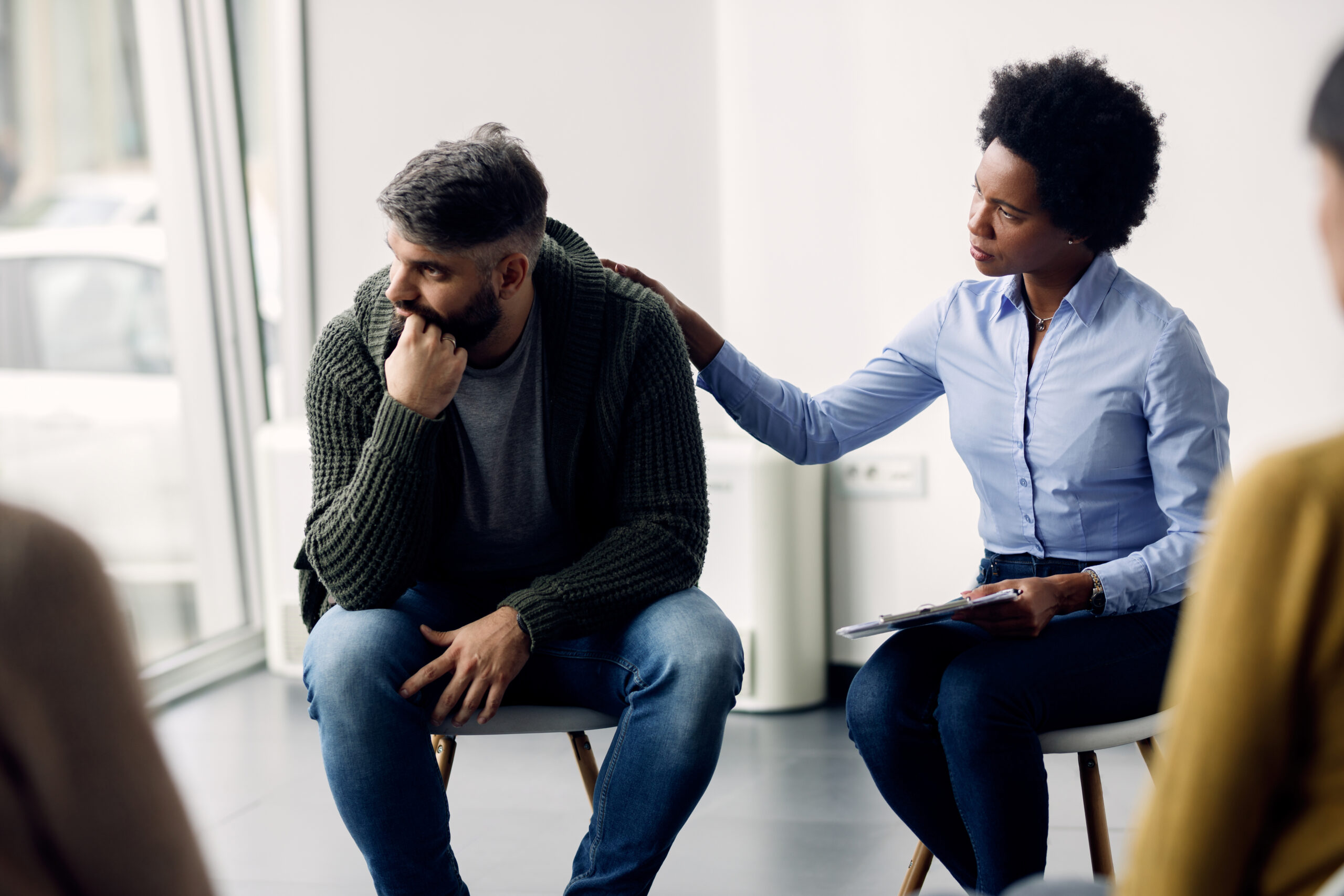 Black female therapist supporting a man who is talking abut his